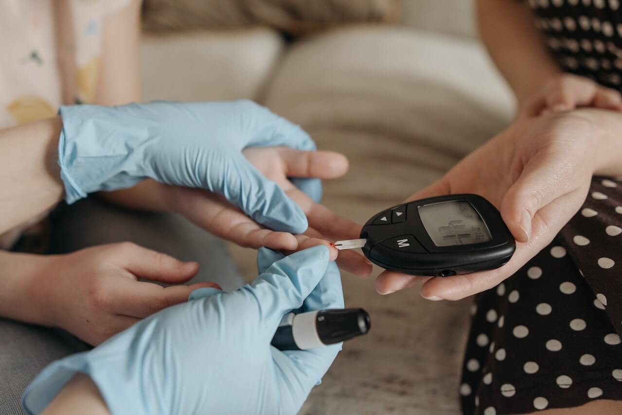 Diabetes blood glucose test with gloved hand and digital glucometer
