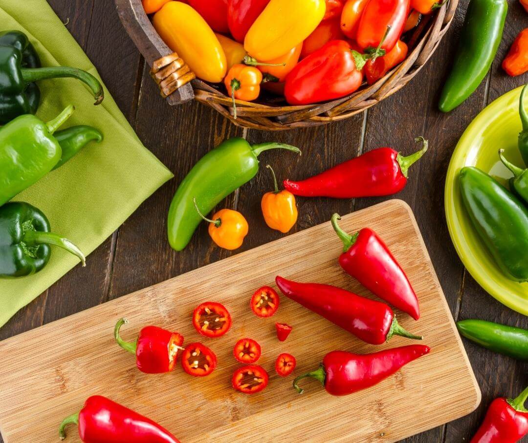 Colorful variety of fresh chili peppers on wooden board and basket