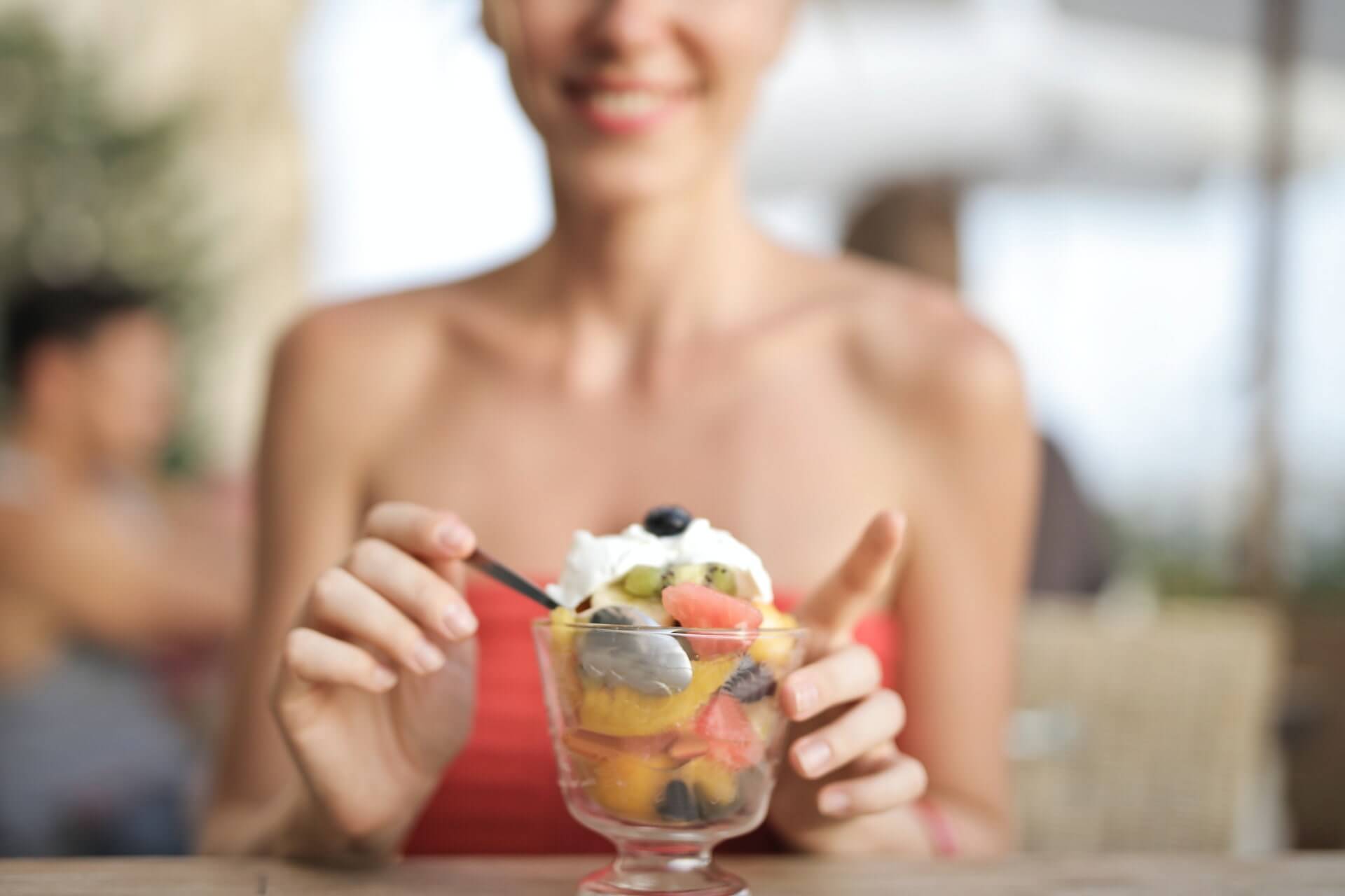 Colorful fruit parfait in glass with whipped cream and mixed fruits