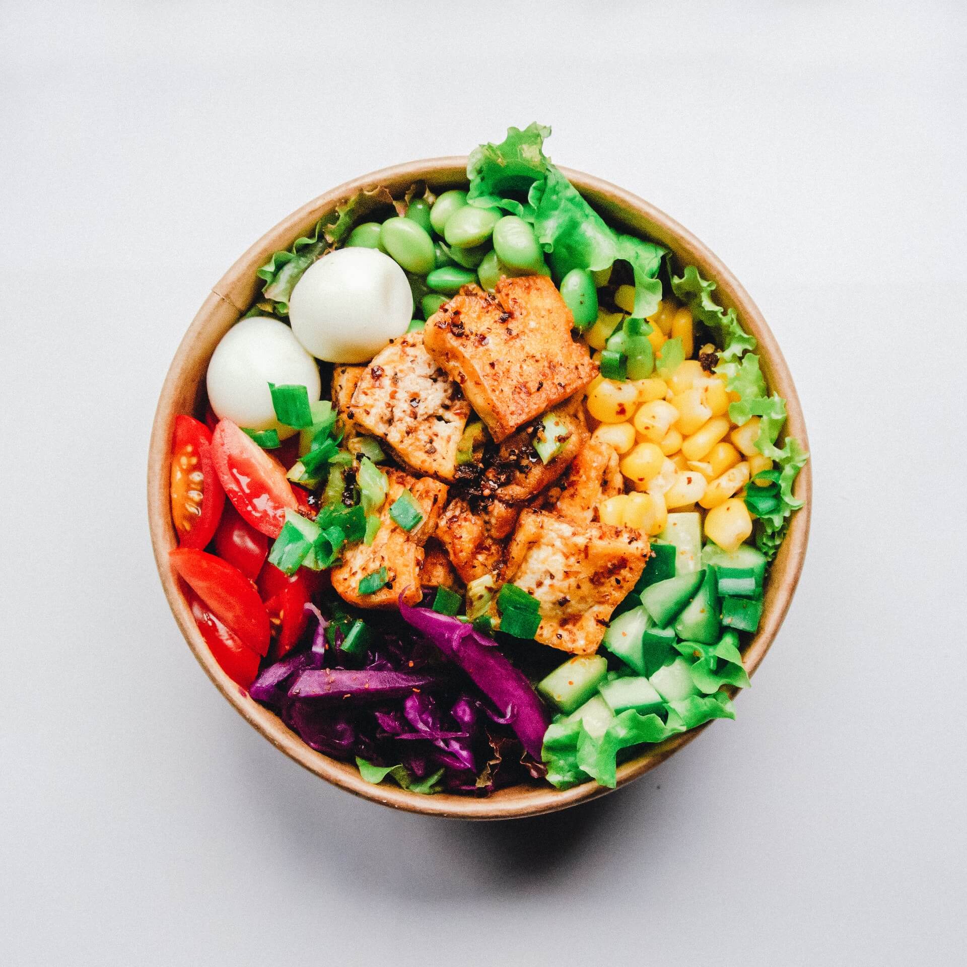 Colorful salmon poke bowl with eggs, vegetables, and fresh greens