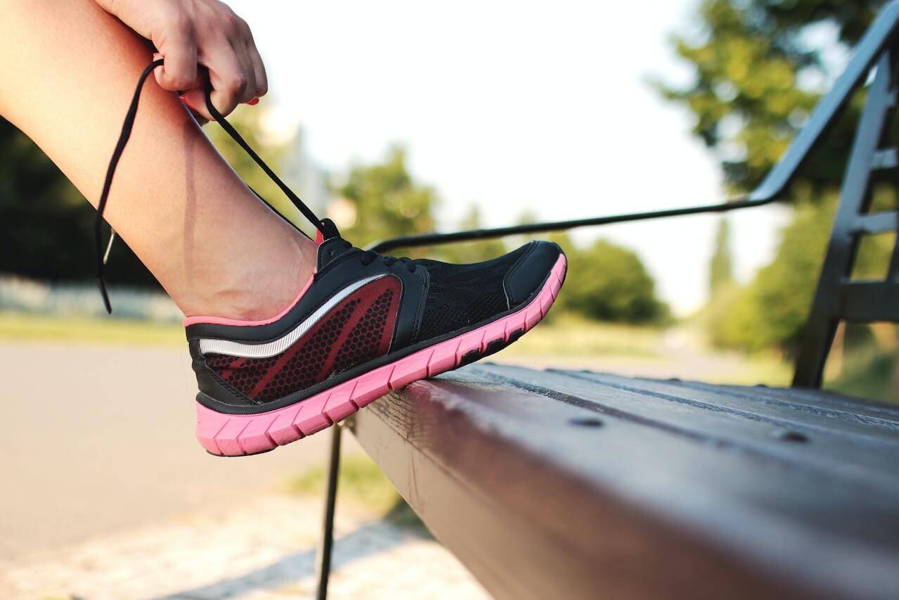 Black and pink running shoe on wooden bench during outdoor workout