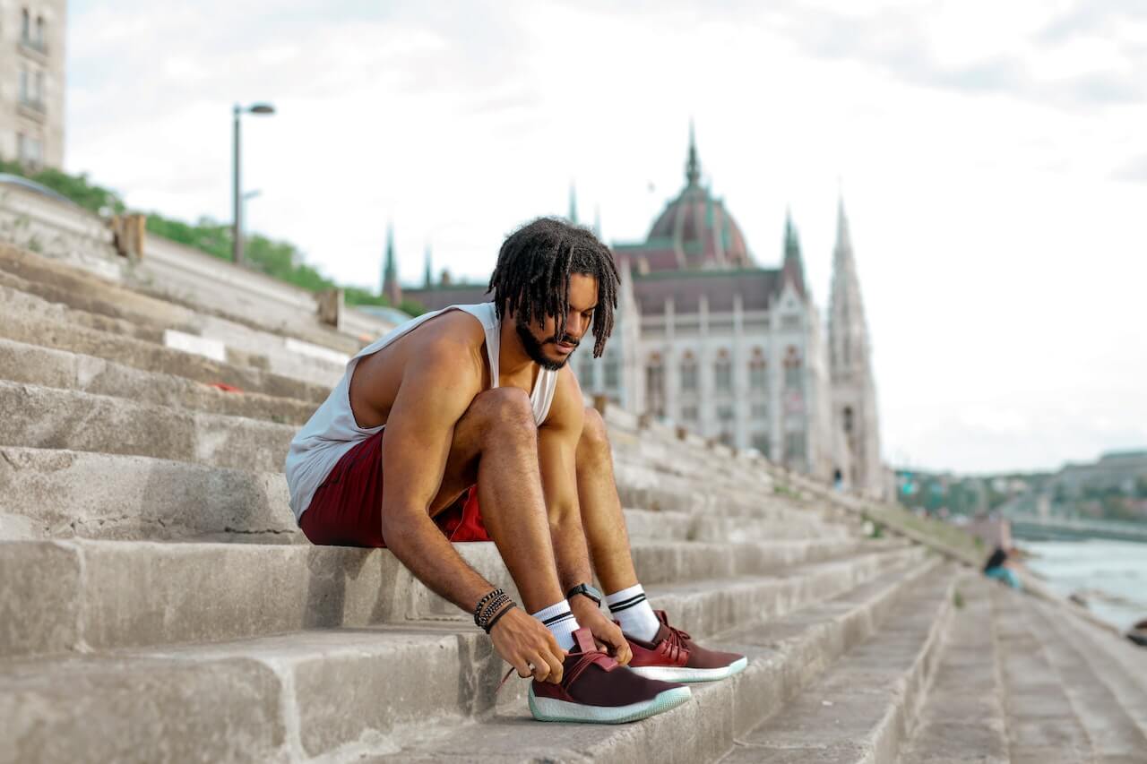Person tying shoelaces on steps with Hungarian Parliament building background