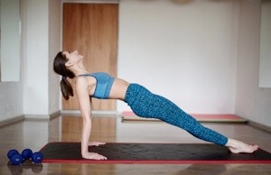 Woman in blue performing yoga or pilates pose on exercise mat