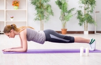 Woman doing plank exercise on purple yoga mat at home