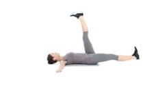 Person in gray clothing performing a lying leg raise exercise