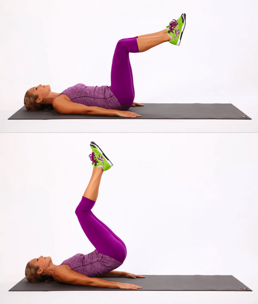 Woman performing leg raise exercise on yoga mat in purple athletic wear