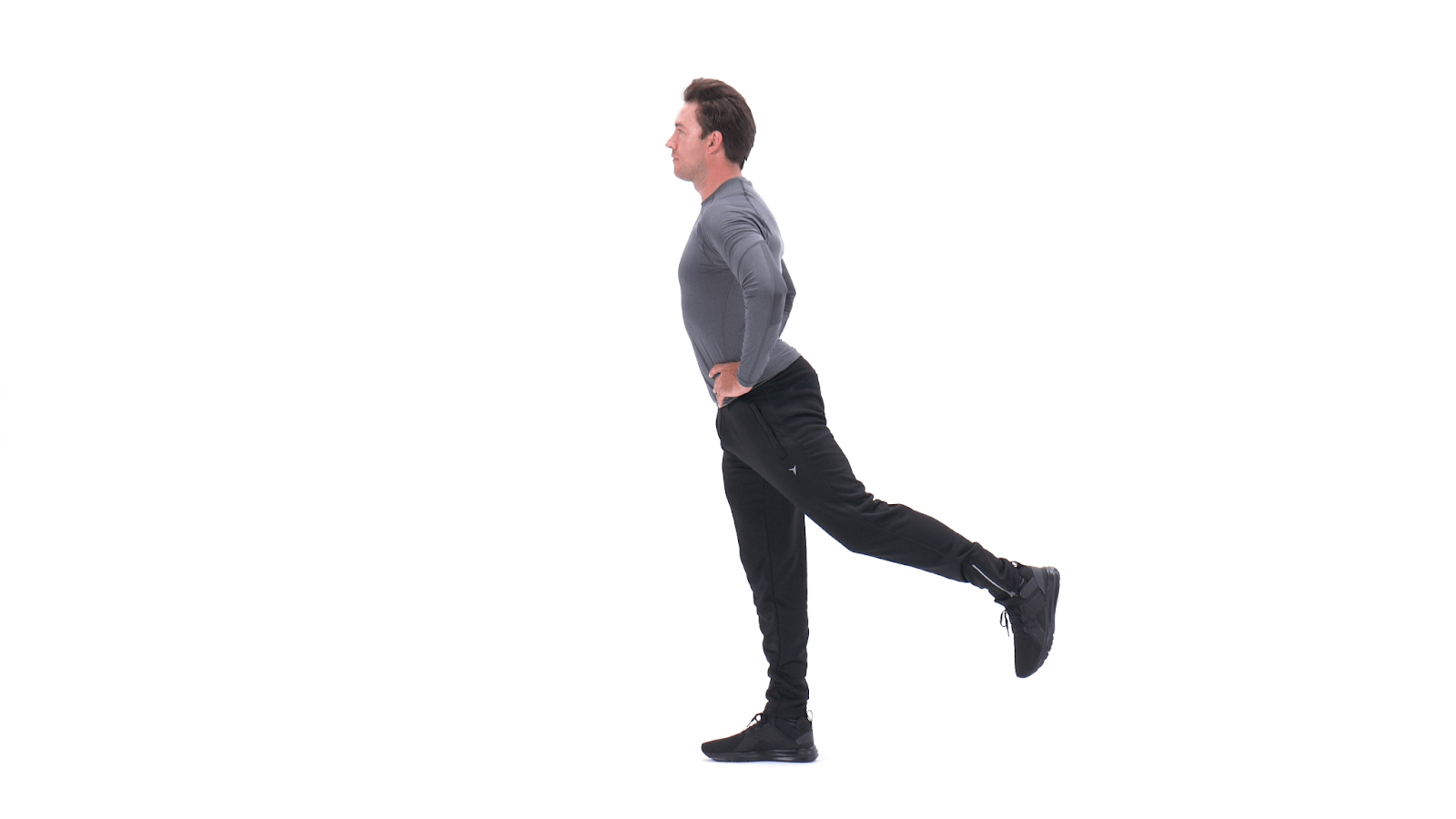 Person in gray shirt doing a standing leg stretch exercise