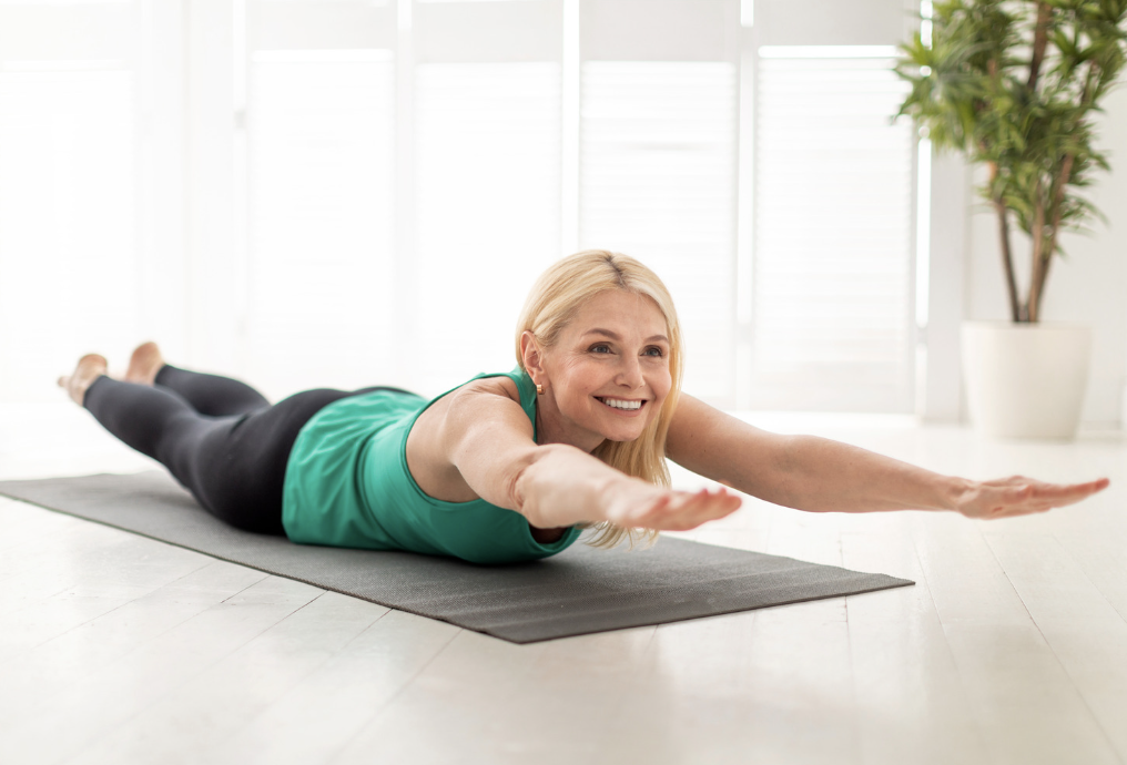 Woman doing back extension exercise on yoga mat at home