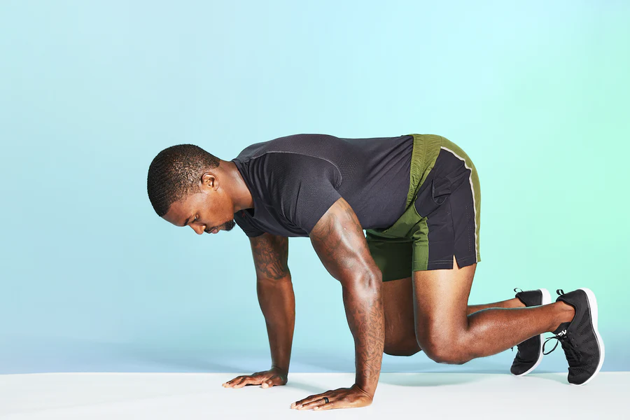 Athletic person in starting position, preparing for exercise on blue background