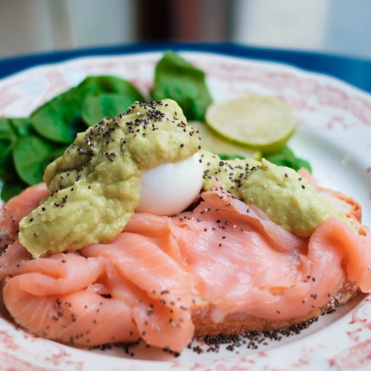 Smoked salmon with poached egg, avocado, and poppy seeds on plate