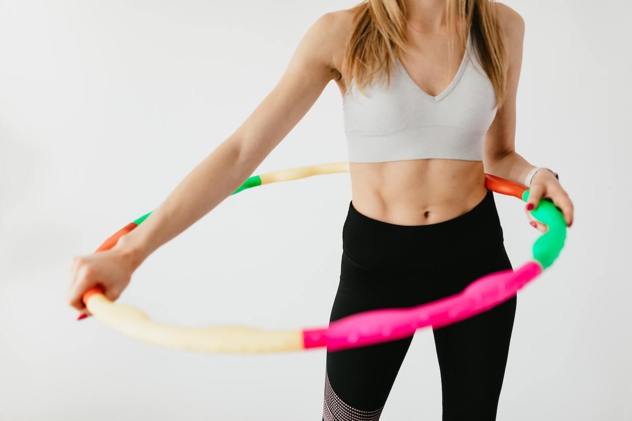 Fitness model twirling colorful hula hoop during exercise routine