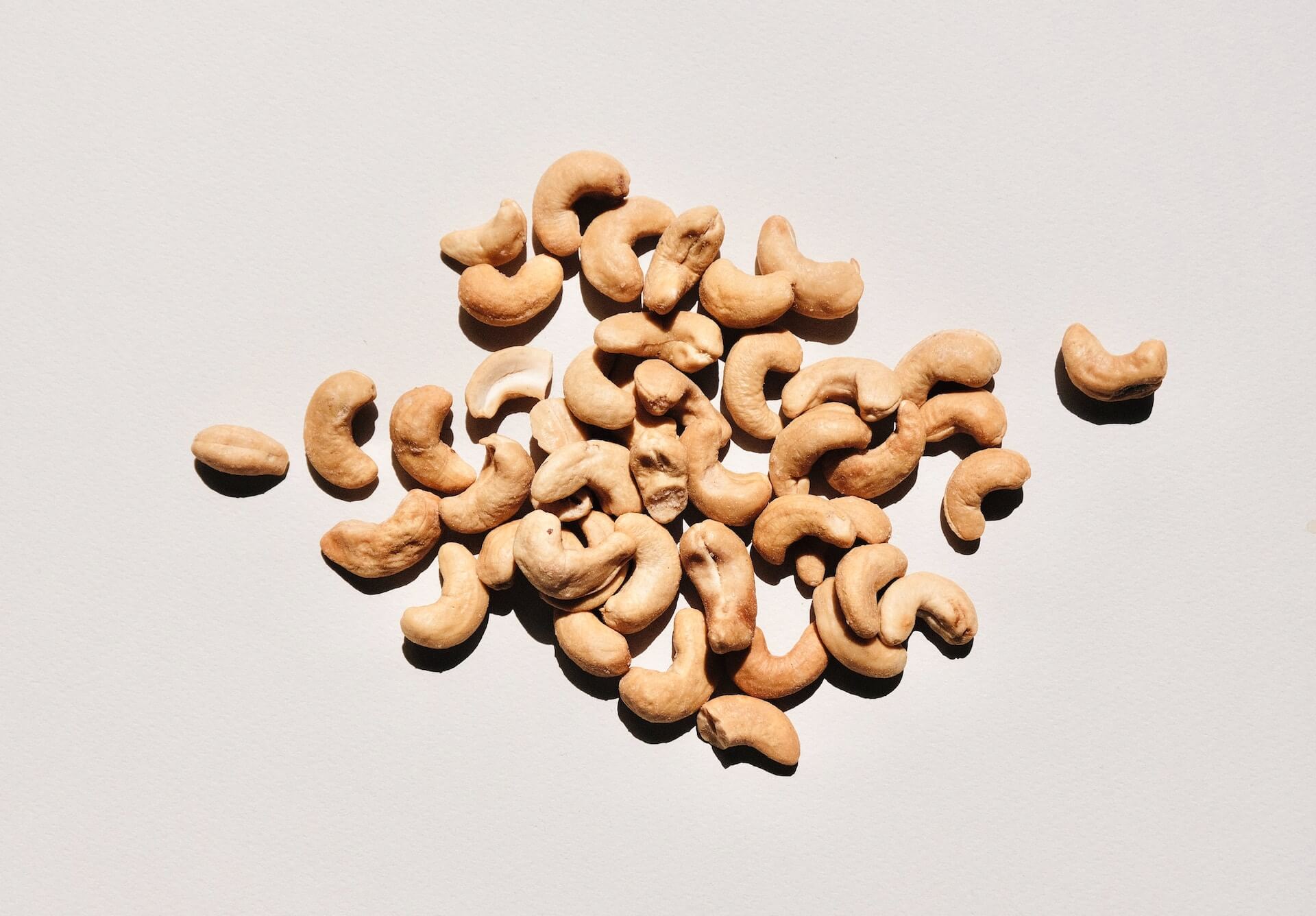 Scattered raw cashew nuts on a white background