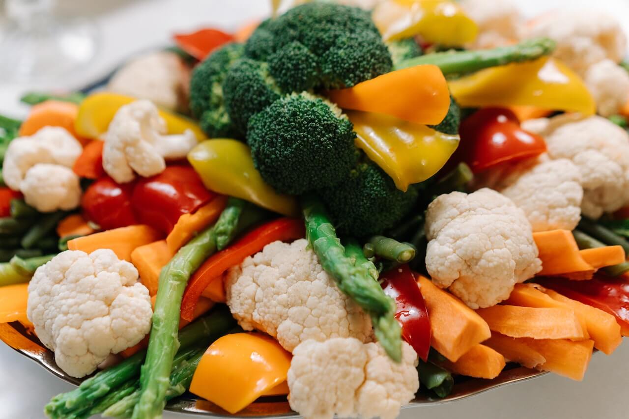 Colorful fresh vegetables including broccoli, cauliflower, peppers, and asparagus