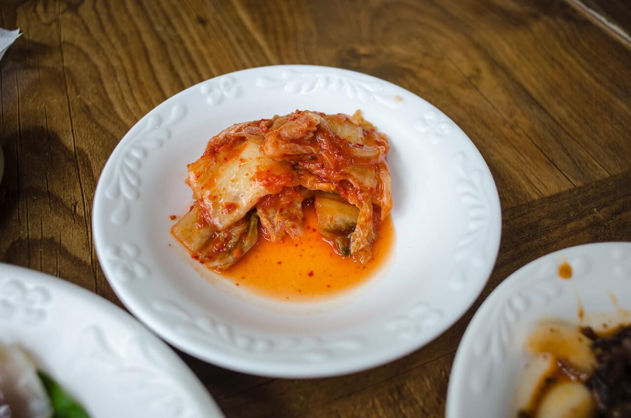Spicy kimchi served on a white decorative plate with orange sauce
