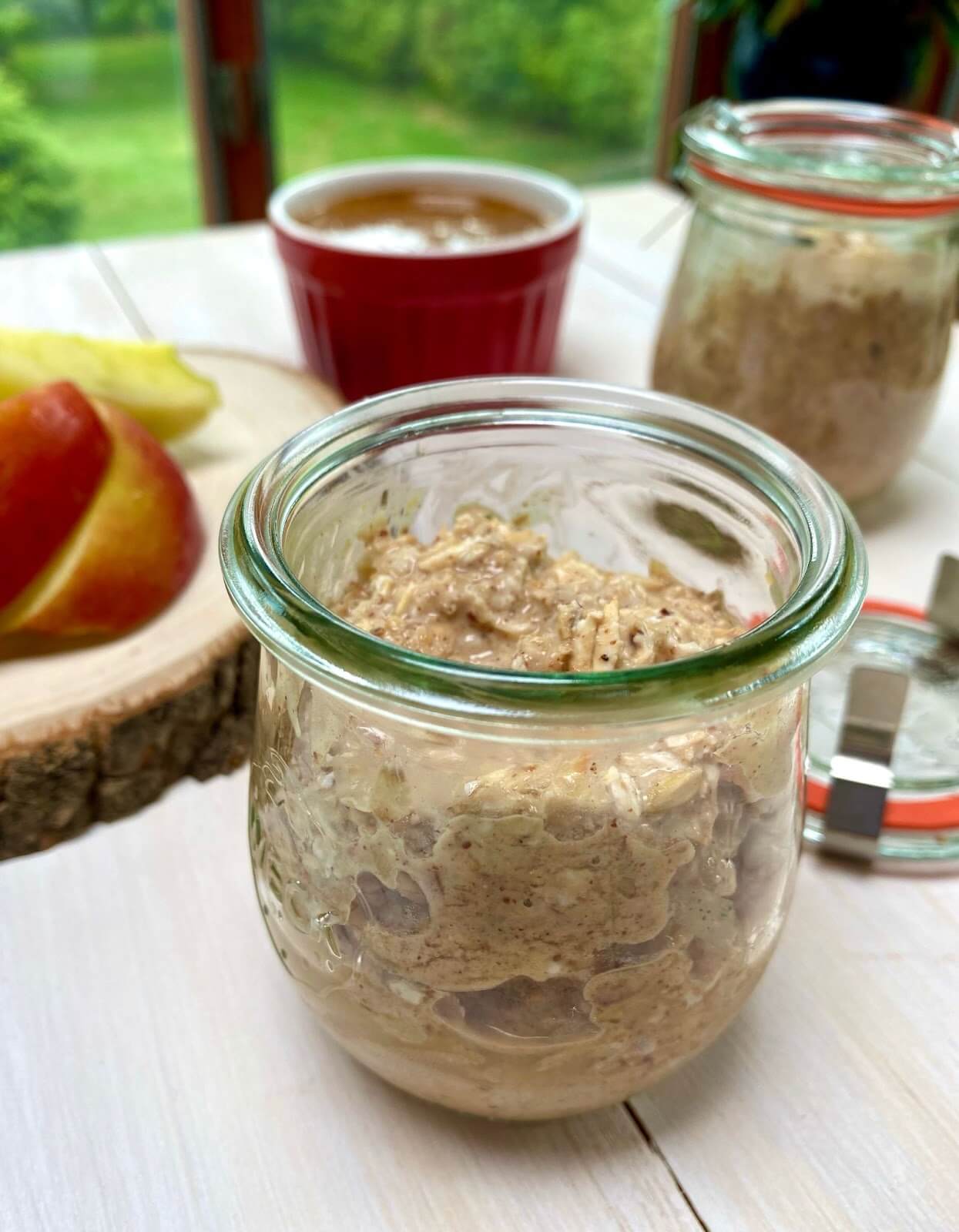 Overnight oats in a glass jar with fruit and red cup in background