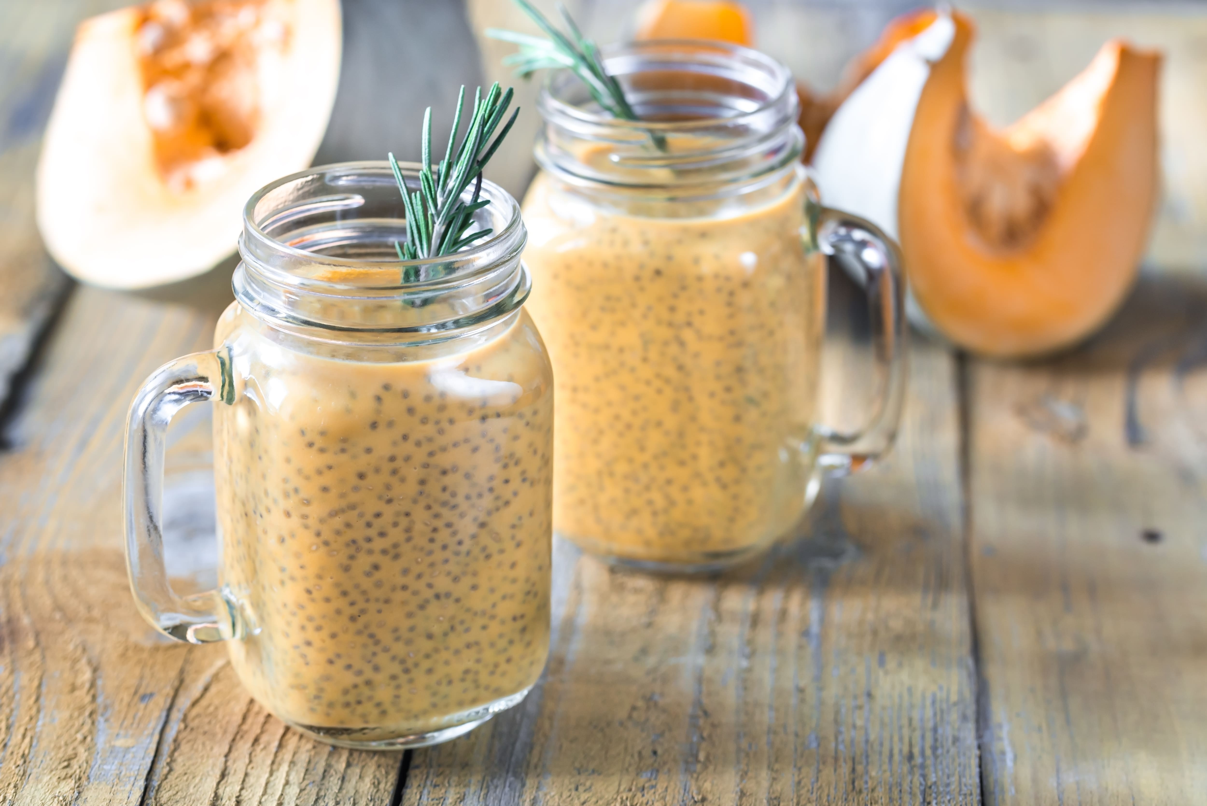 Two mason jars with creamy smoothie drinks garnished with fresh rosemary sprigs and apple slices