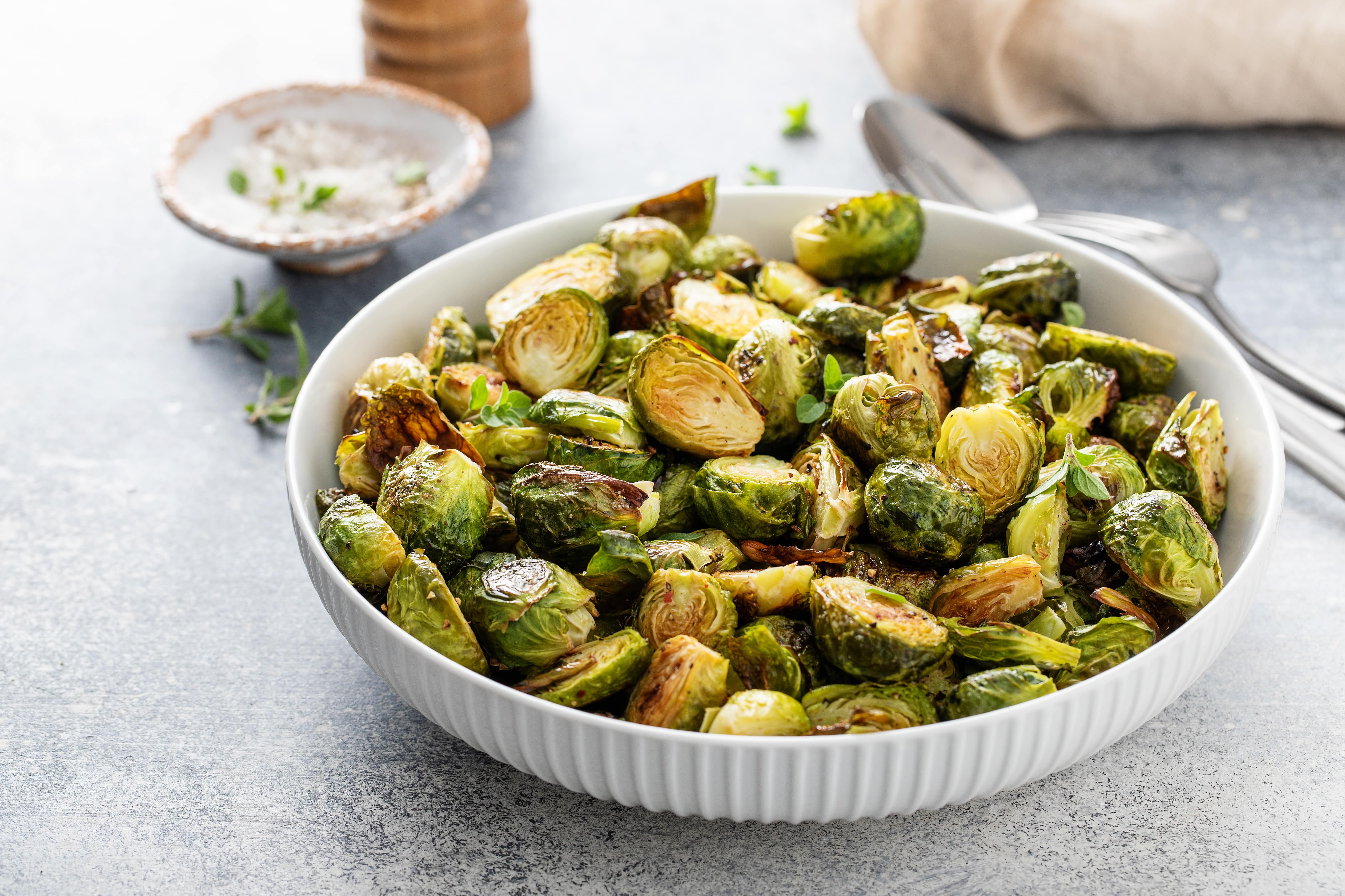 Roasted Brussels sprouts in white bowl with caramelized edges and garnish