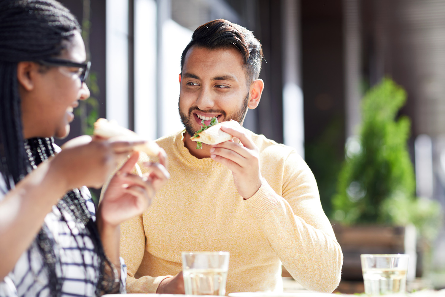 Two people eating lunch together outdoors at a table with drinks