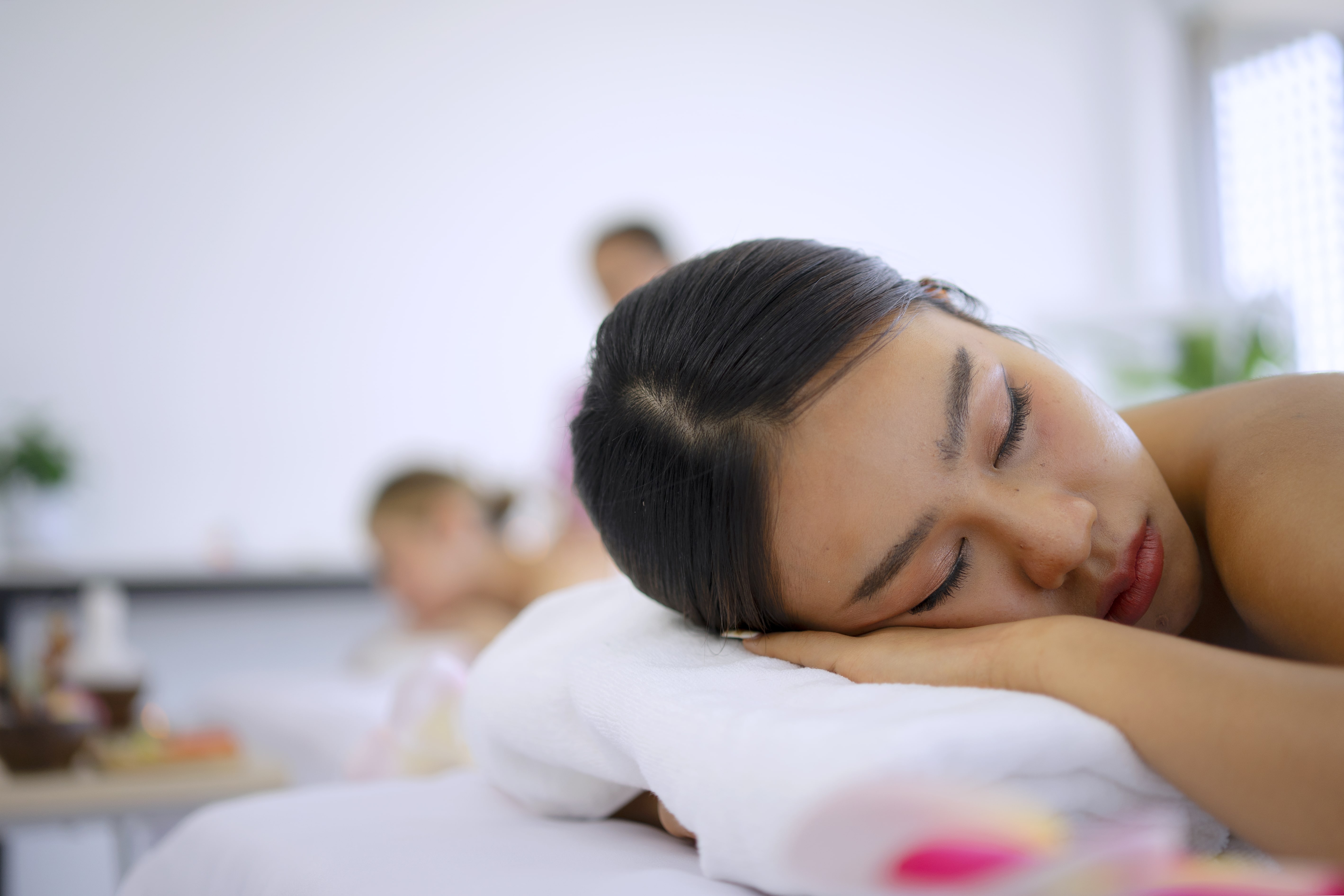 Woman resting peacefully at spa with eyes closed on massage table