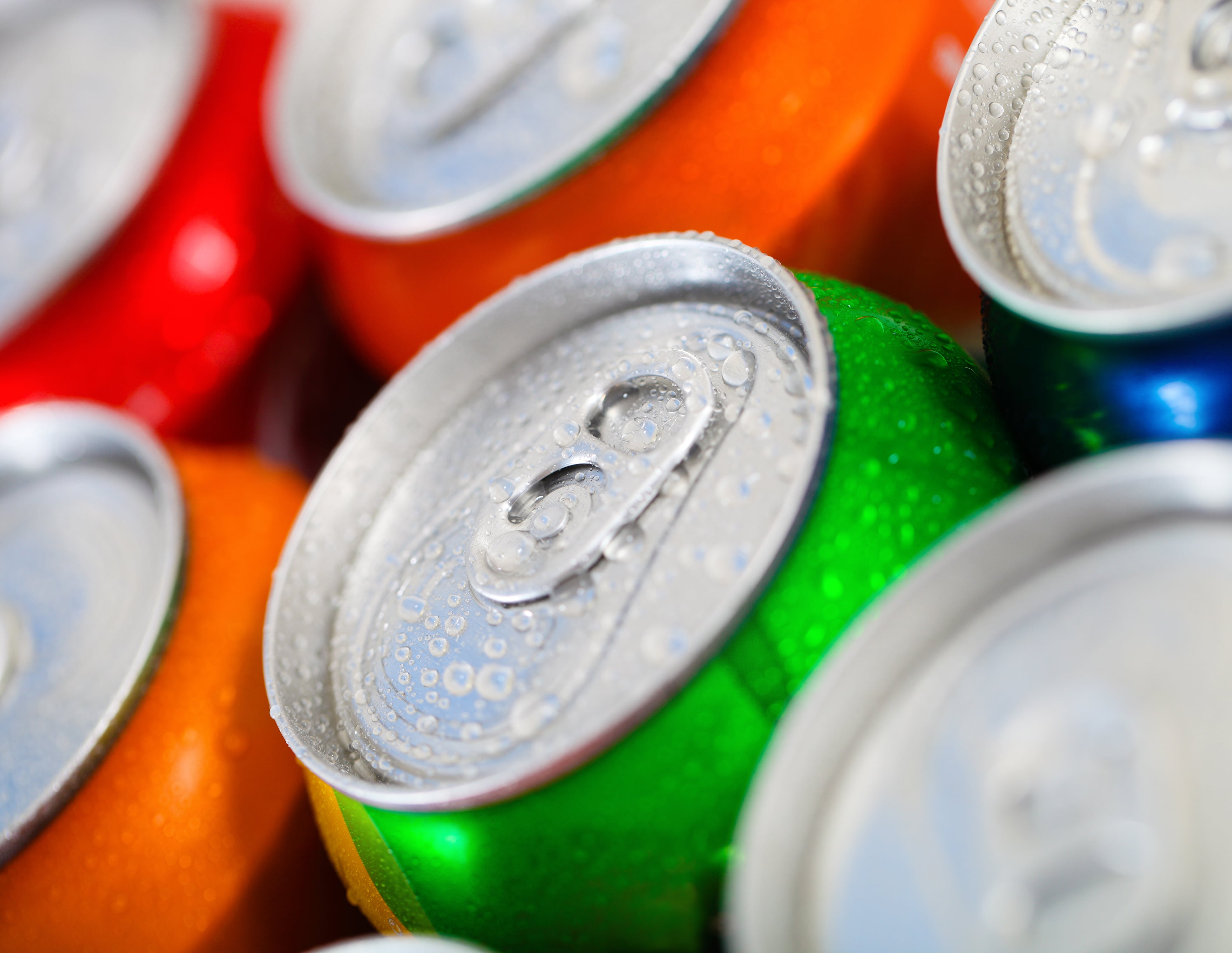Close-up of wet aluminum beverage can tops in colorful red, orange, green bottles