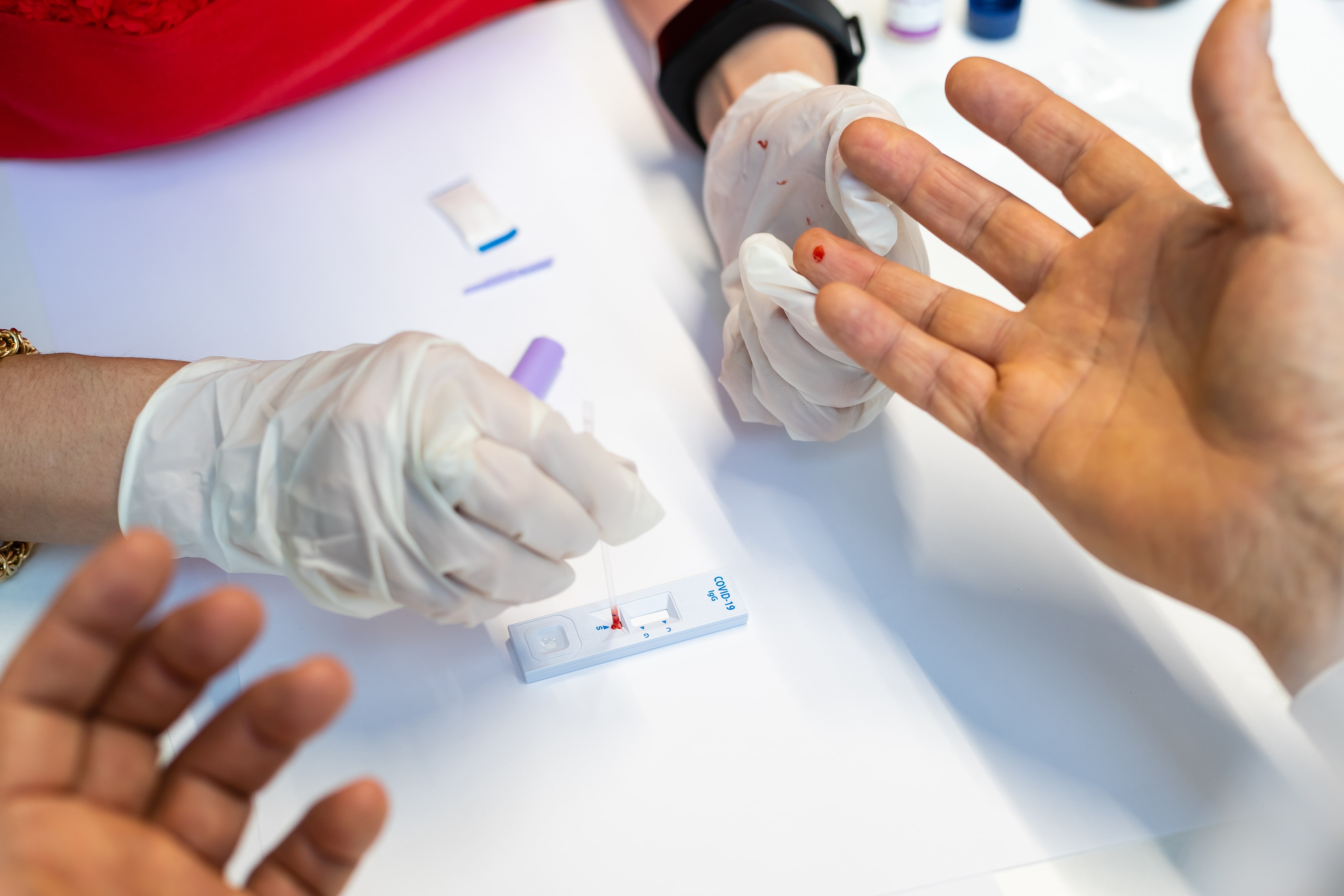 Medical professionals wearing gloves performing blood test with rapid COVID diagnostic test kit