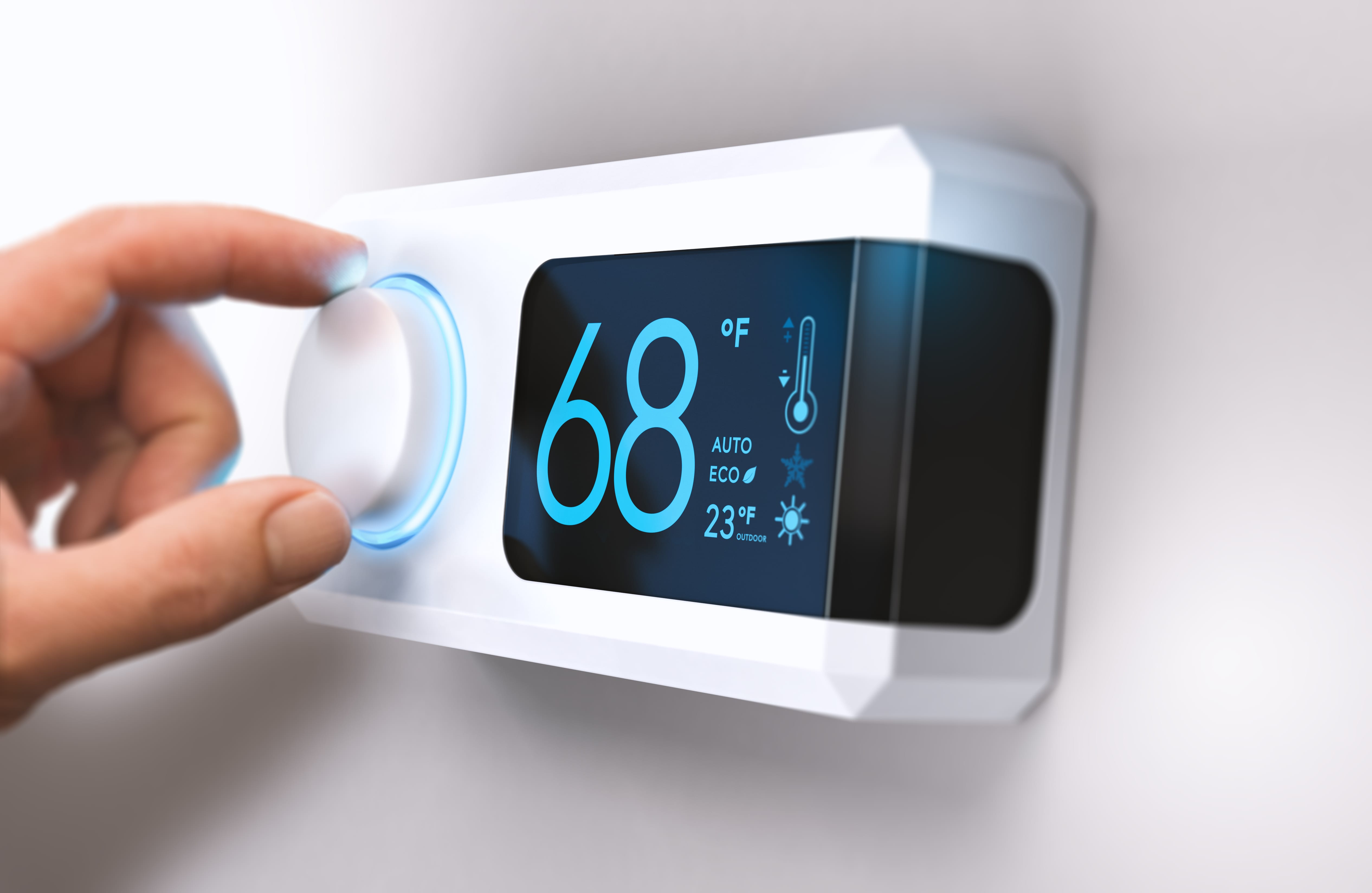 Hand adjusting digital thermostat displaying 68 degrees Fahrenheit and outdoor temperature
