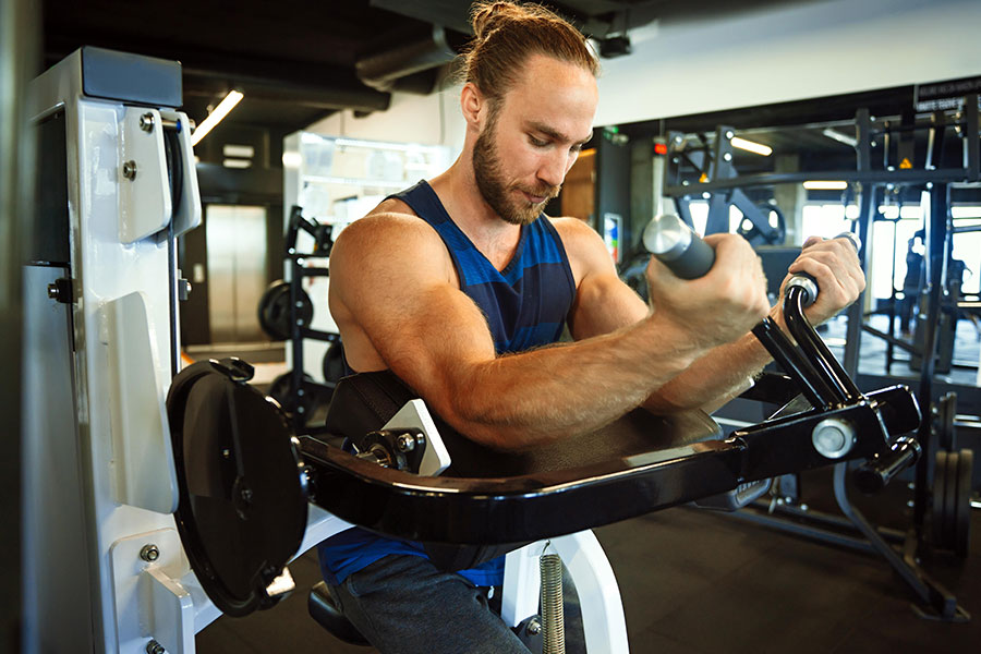 Man doing bicep curls with dumbbells in modern gym setting.