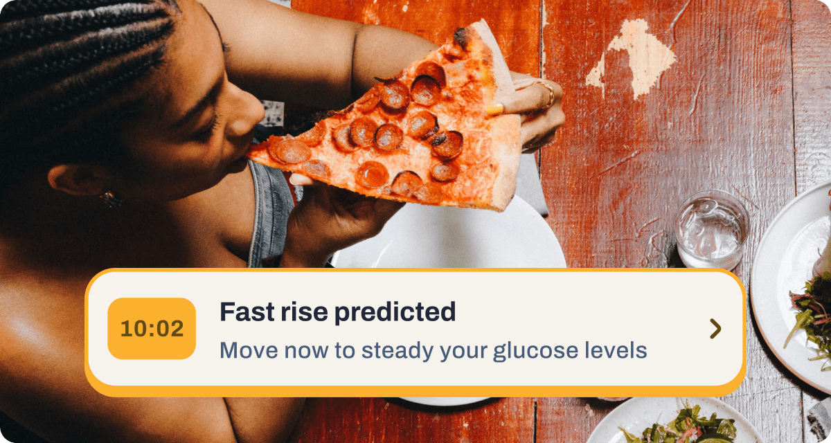 Person eating pepperoni pizza with glucose alert notification at 10:02