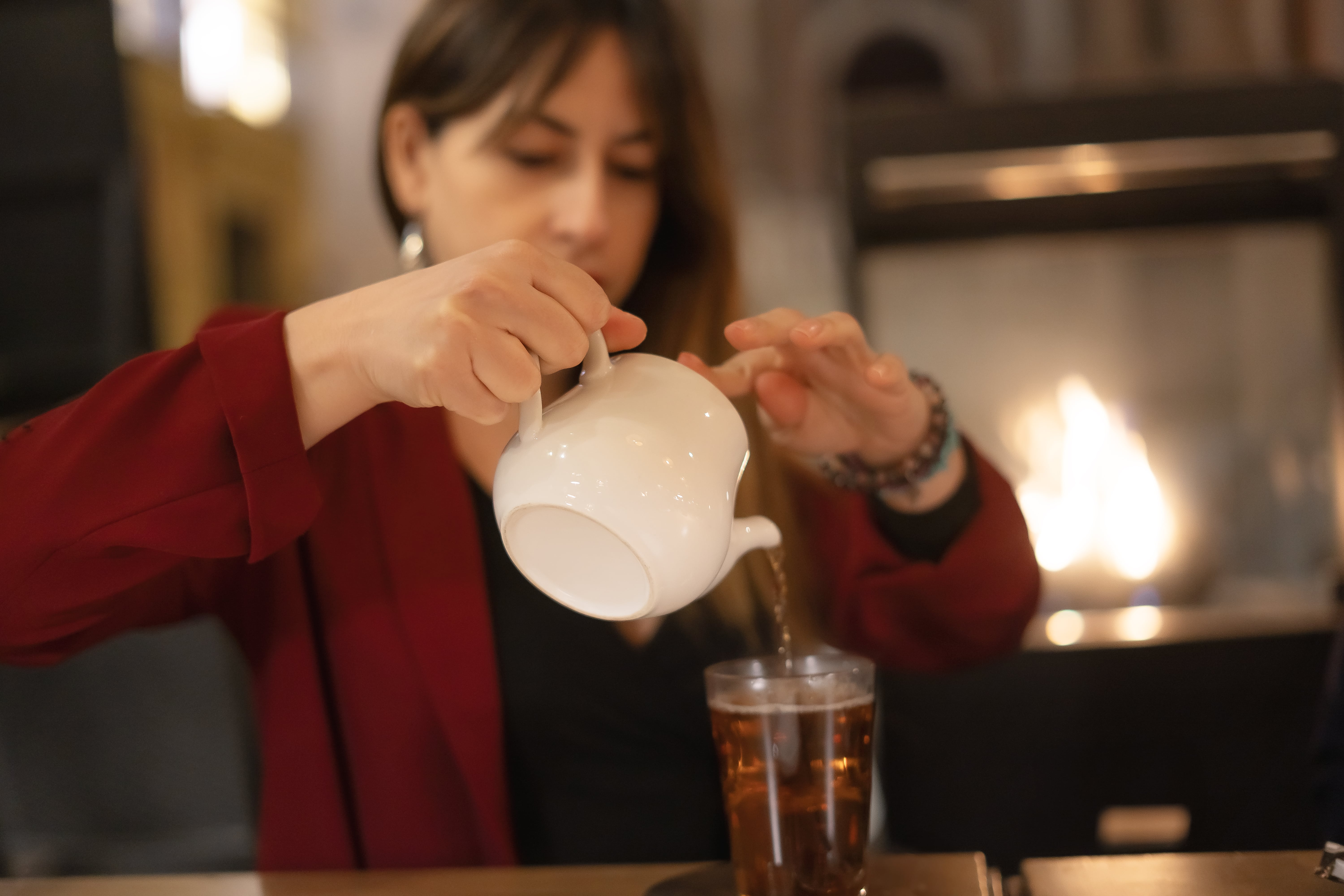 Woman in red jacket pouring water into a glass from a pitcher