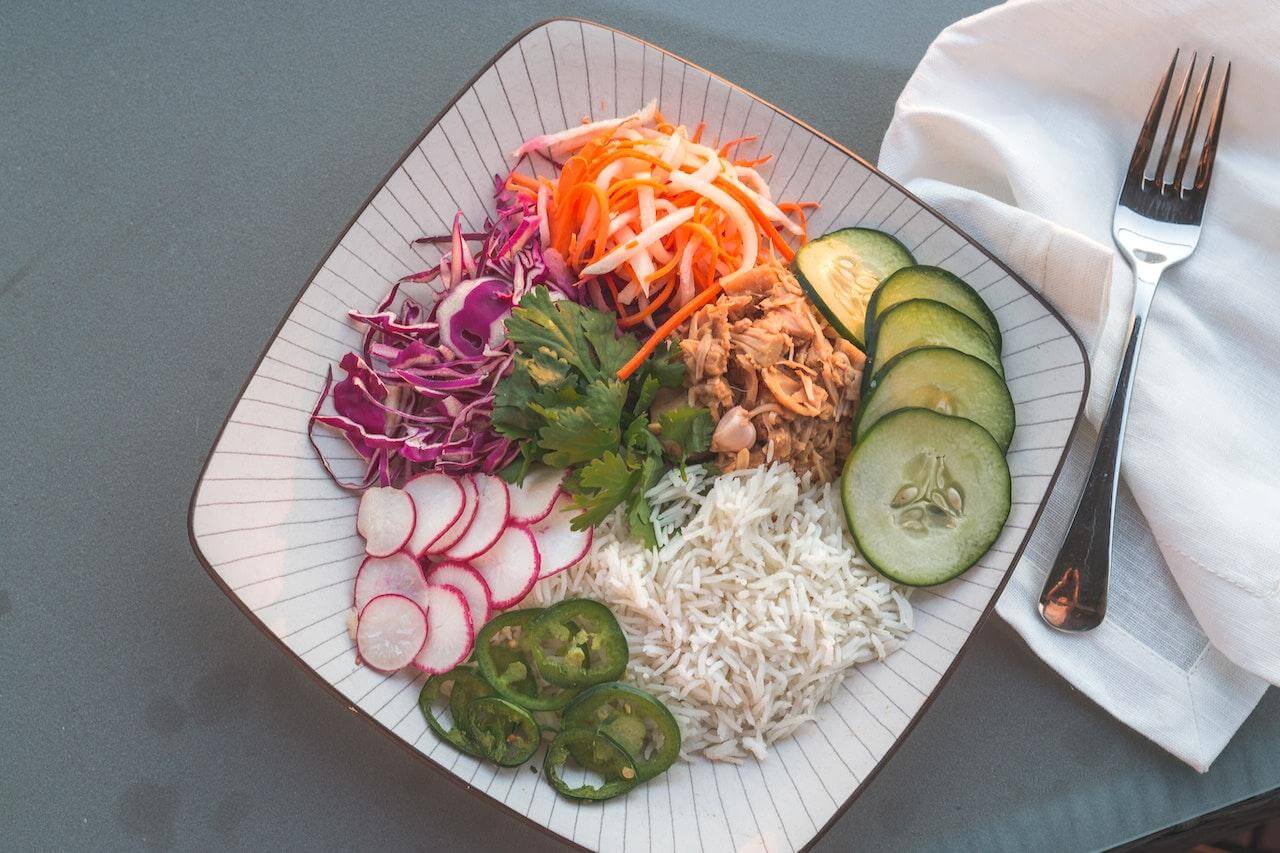 Colorful Vietnamese salad plate with shredded vegetables, rice, herbs, and fork on napkin