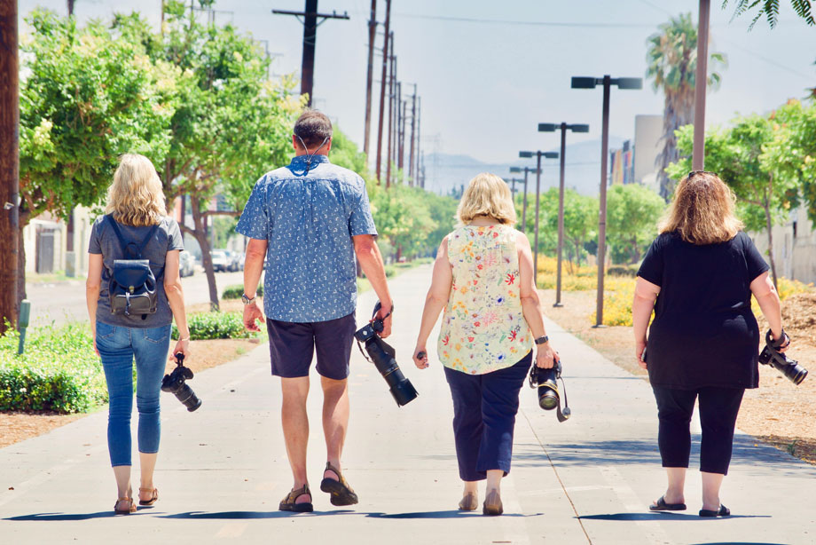 Four people jogging together on a tree-lined suburban street with power lines visible.