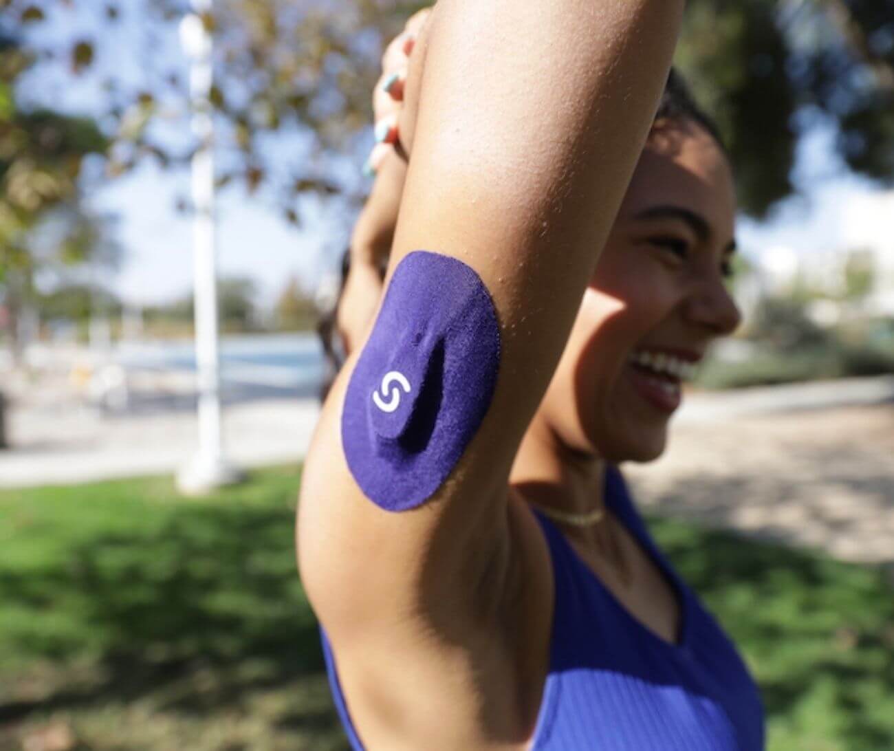 Athlete wearing blue kinesiology tape on arm outdoors at sports facility