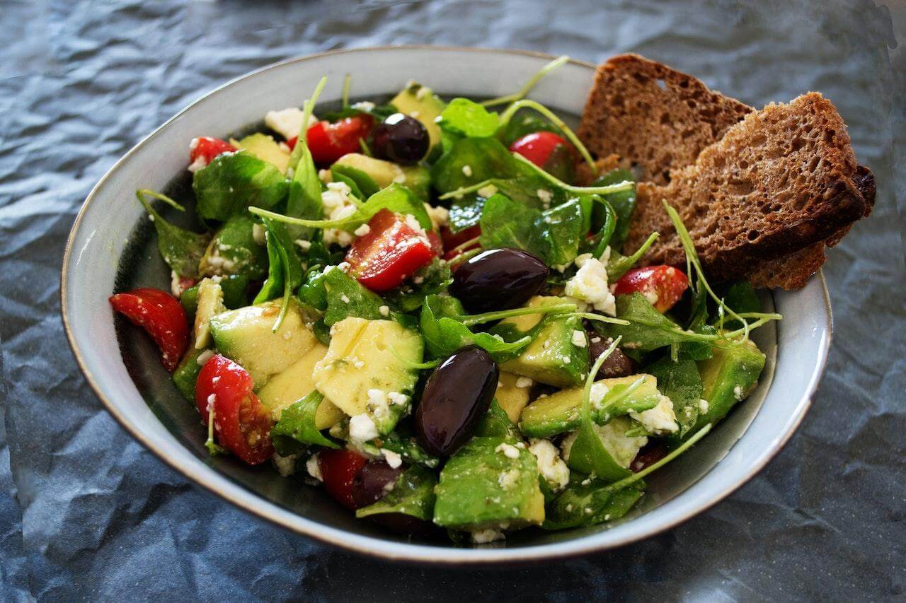 Mediterranean salad with greens, tomatoes, olives, feta, and toasted bread slices