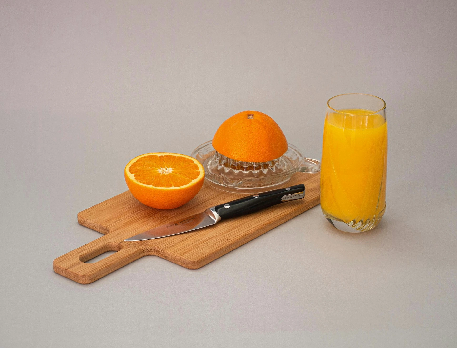 Fresh orange and juicer with glass of orange juice on wooden board