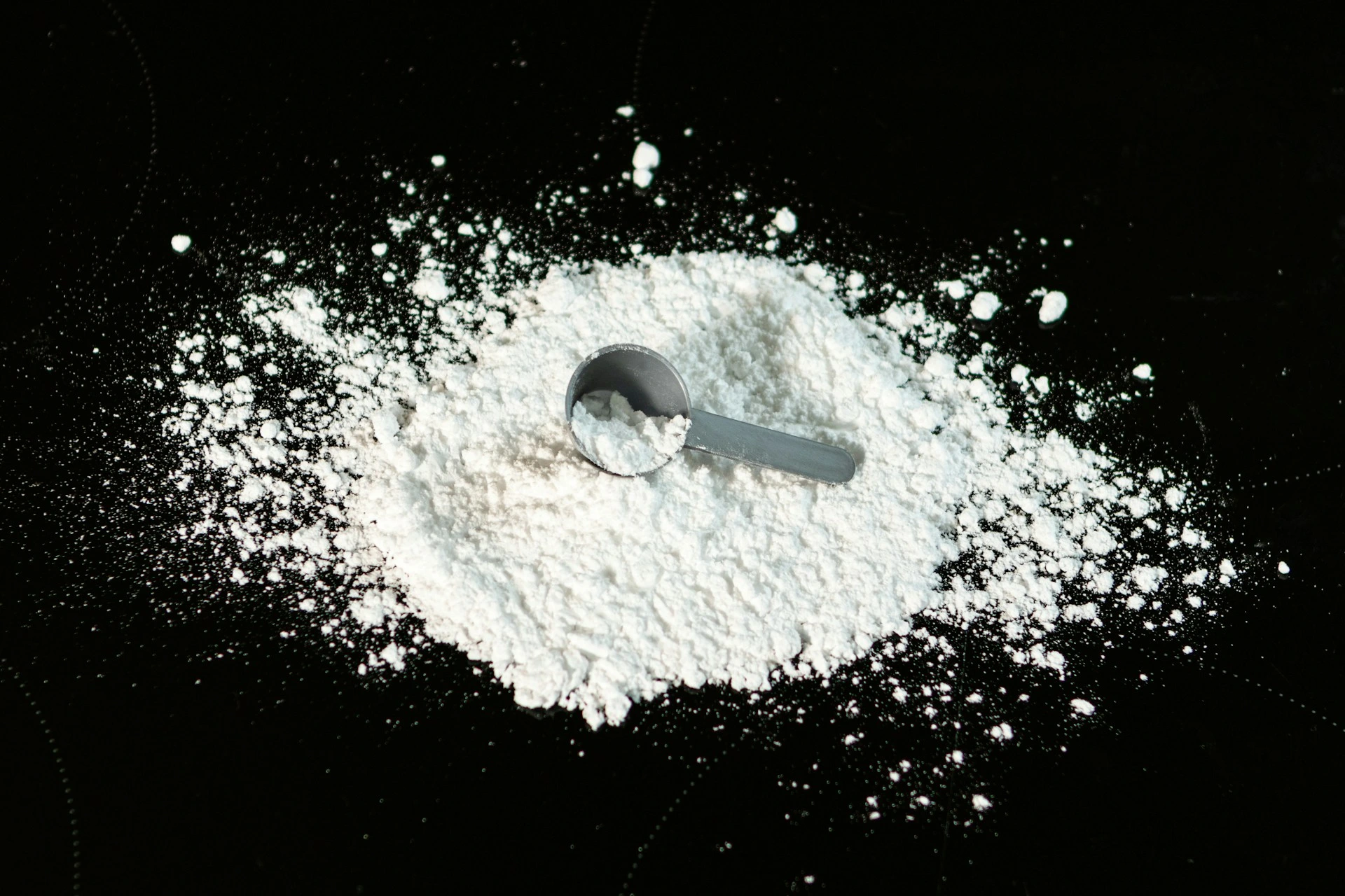 White powder with measuring scoop on black background