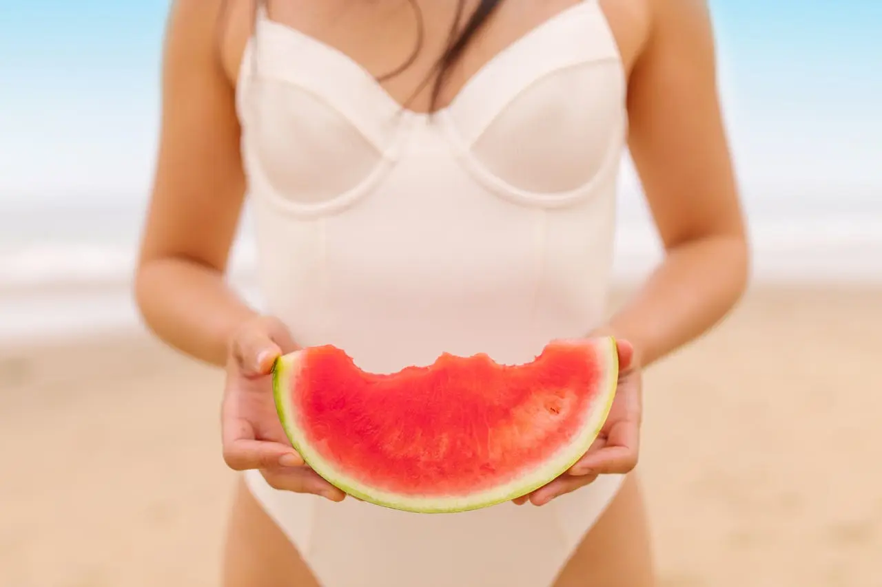 Person holding a juicy watermelon slice at the beach