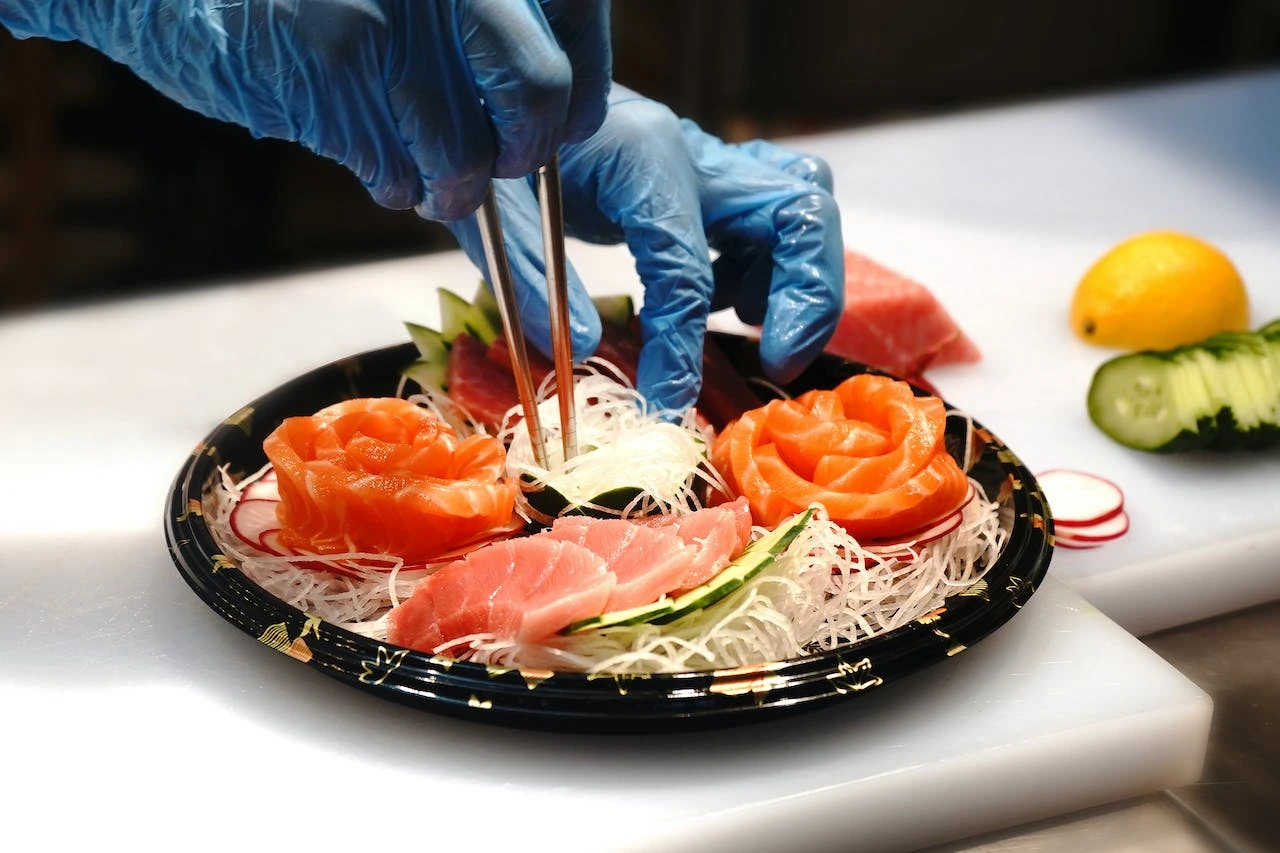 Chef preparing sashimi with salmon roses on decorative plate