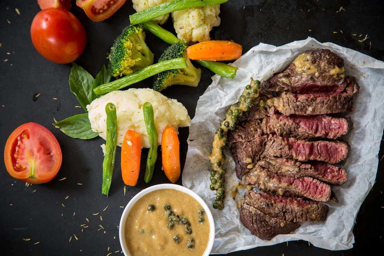 Medium-rare steak with roasted vegetables, cauliflower, and mustard sauce
