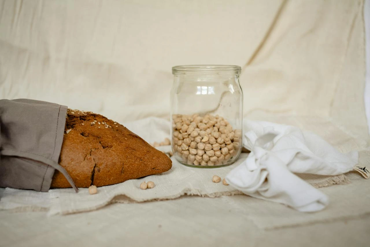 Rustic bread loaf with sesame seeds and glass jar of chickpeas