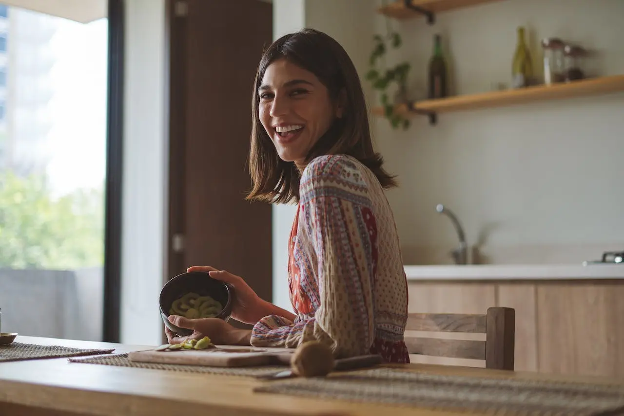 Smiling woman preparing food in bright kitchen by window