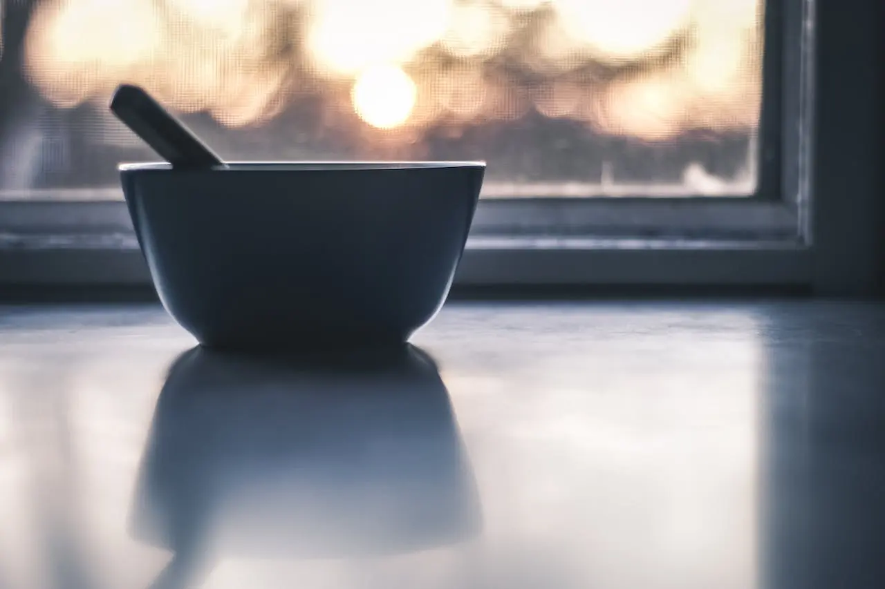Black mortar and pestle on windowsill with soft sunrise light