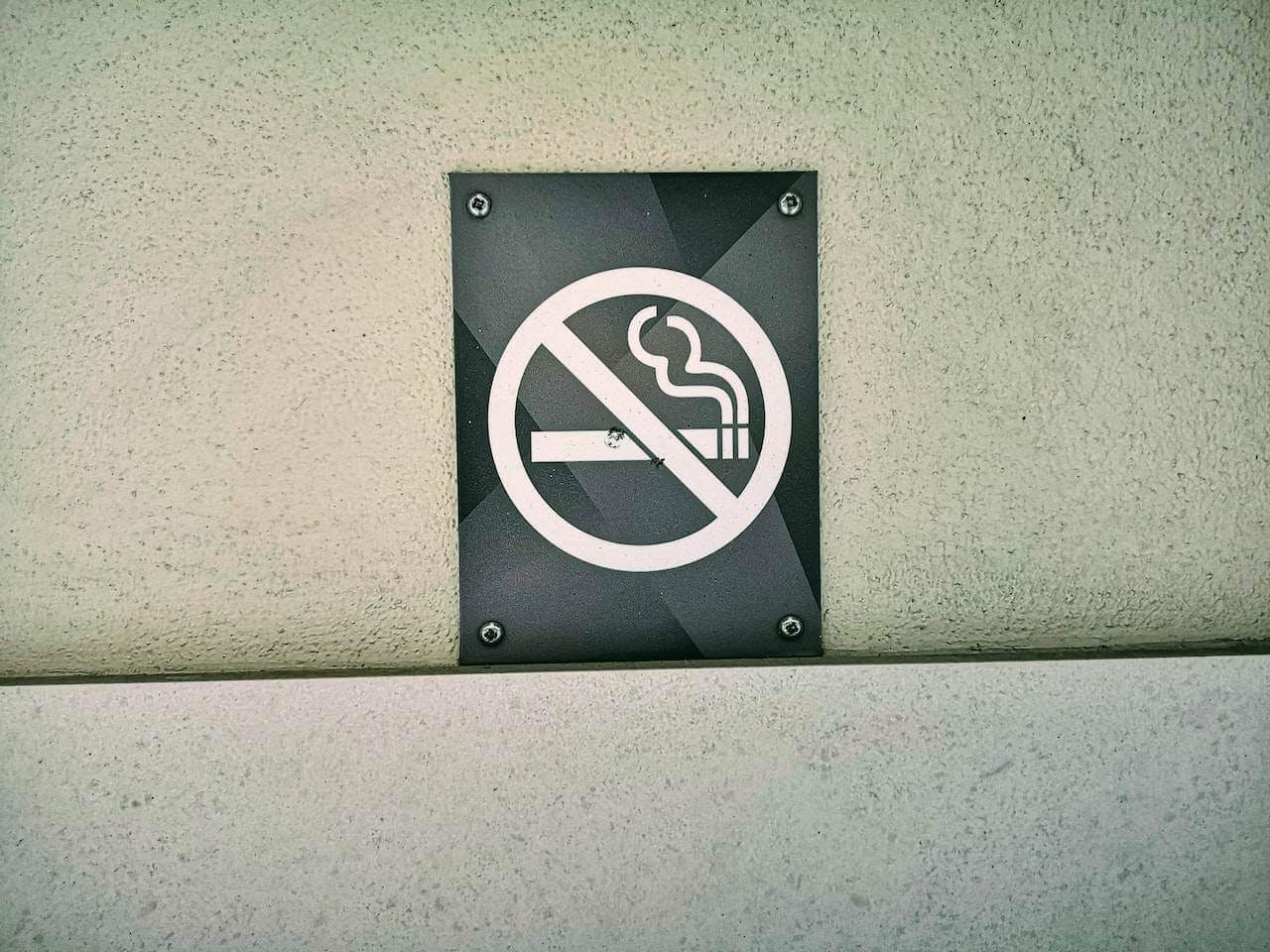 No smoking sign mounted on textured wall with black background