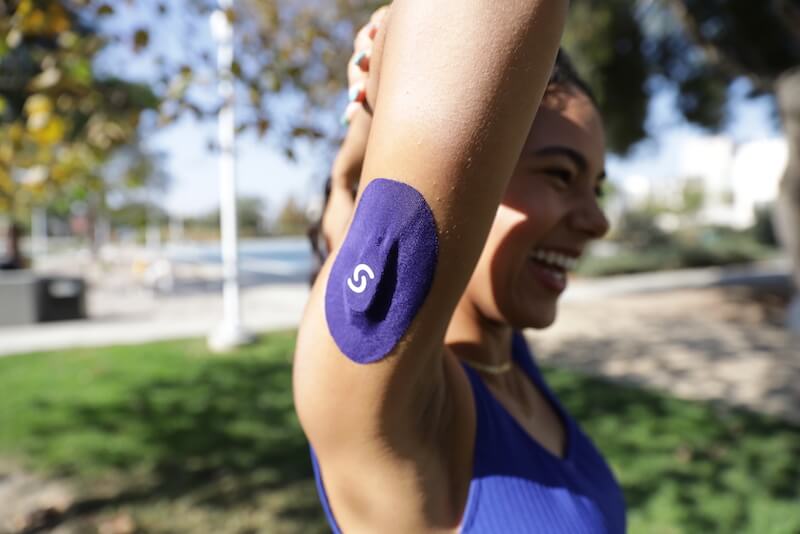 Woman wearing CGM and Signos patch on her left arm