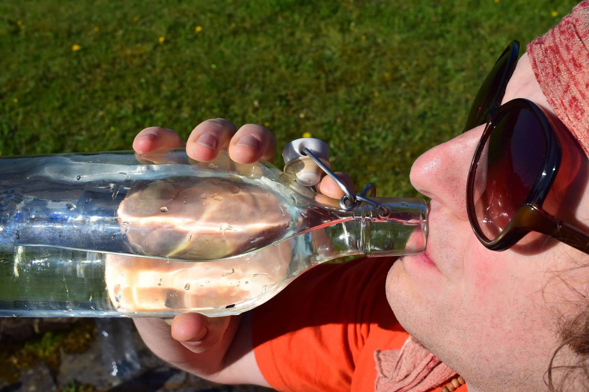 Person-drinking-water-from-glass-bottle-urine-glucose-test