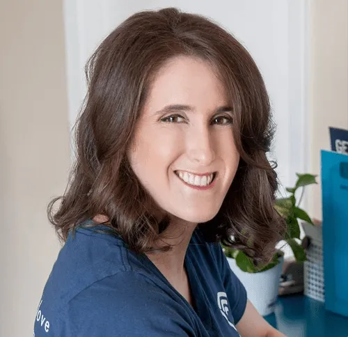 Professional woman smiling in blue shirt with office plant background