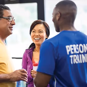 Three fitness professionals talking and smiling in gym or training center
