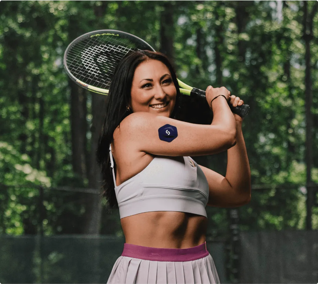 Smiling tennis player holding racket, posing in forest with athletic outfit
