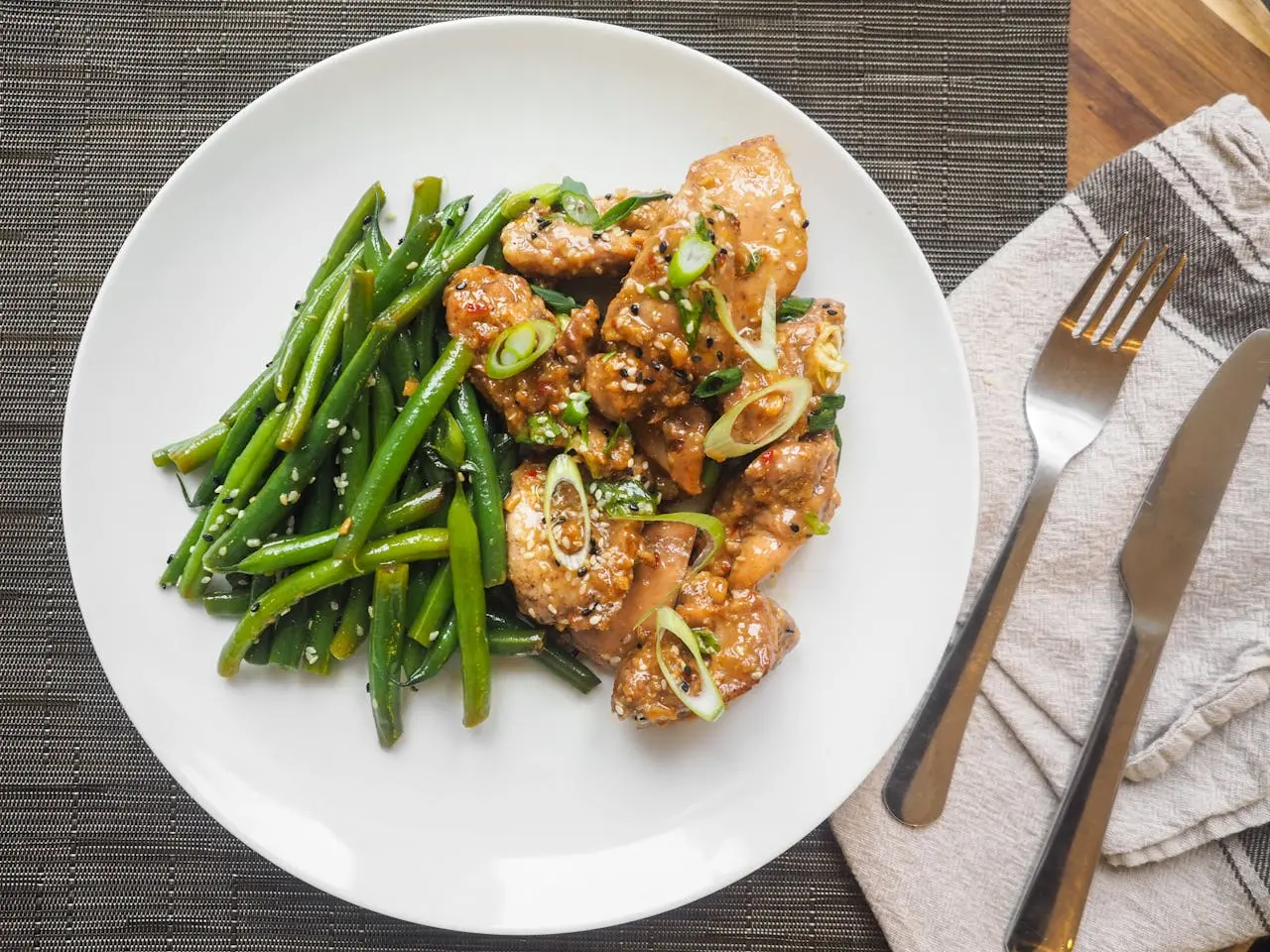 Glazed shrimp with sesame green beans on a white plate