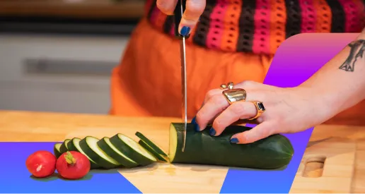 Hands chopping zucchini and tomatoes on a colorful cutting board