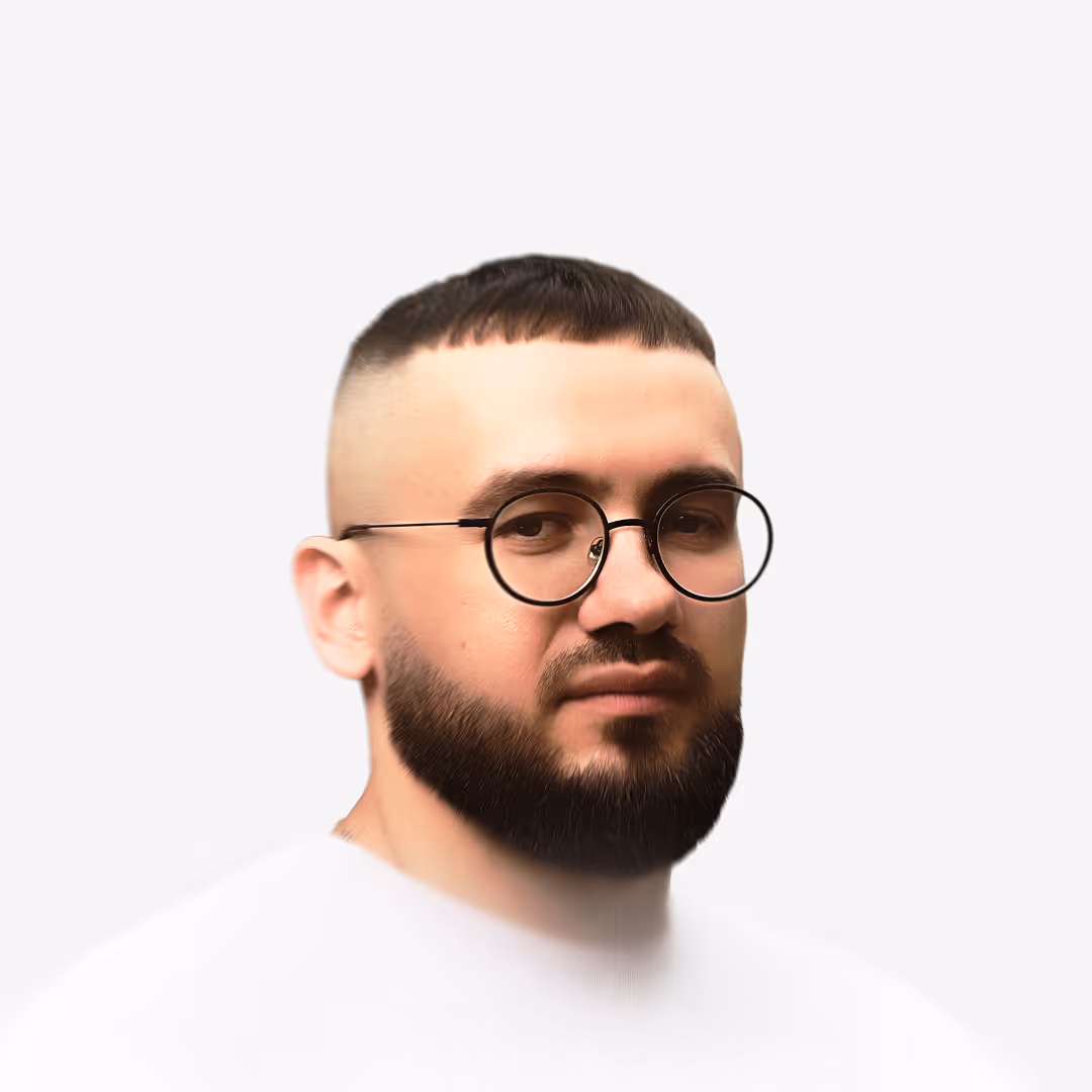 Portrait of a man with round glasses, beard, and short cropped hair with a fade haircut.